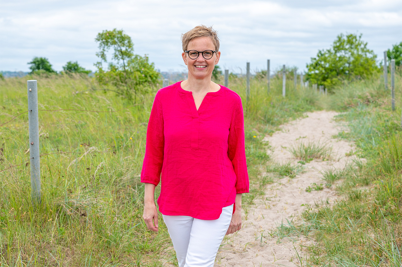 Symbolisch für Achtsamkeitstraining: Marlene Rostig läuft durch die Dünenlandschaft, im Hintergrund Sandweg